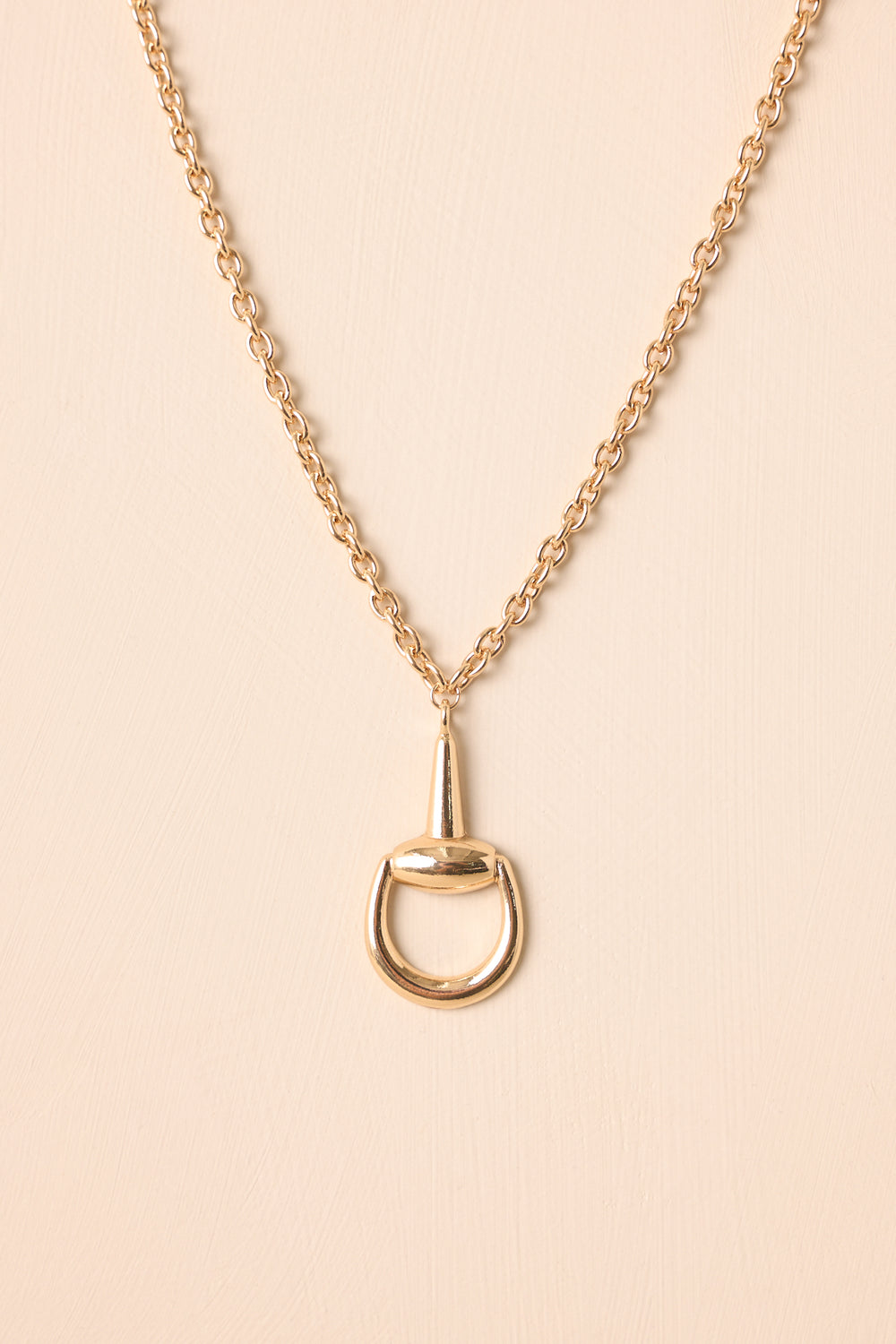 Gold-Stirrup-Pendant-Necklace-Chain-Lobster-Clasp-Beige-Background