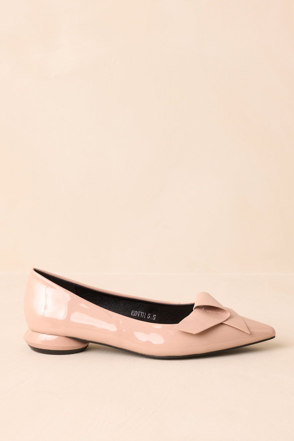 Side-View-Of-Beige-Patent-Flats-Against-A-Beige-Background